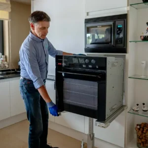 Een inbouwoven herstellen door erkend elektrohersteller Marc Leyre. Met zijn hersteldienst beschikt hij over speciaal gereedschap voor het uitbouwen van inbouwtoestellen. Hier werkt hij met een professionele draagtafel voor keukenapparatuur.