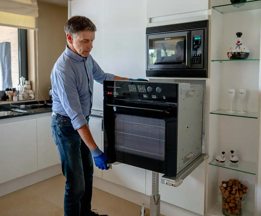 Een inbouwoven herstellen door erkend elektrohersteller Marc Leyre. Met zijn hersteldienst beschikt hij over speciaal gereedschap voor het uitbouwen van inbouwtoestellen. Hier werkt hij met een professionele draagtafel voor keukenapparatuur.