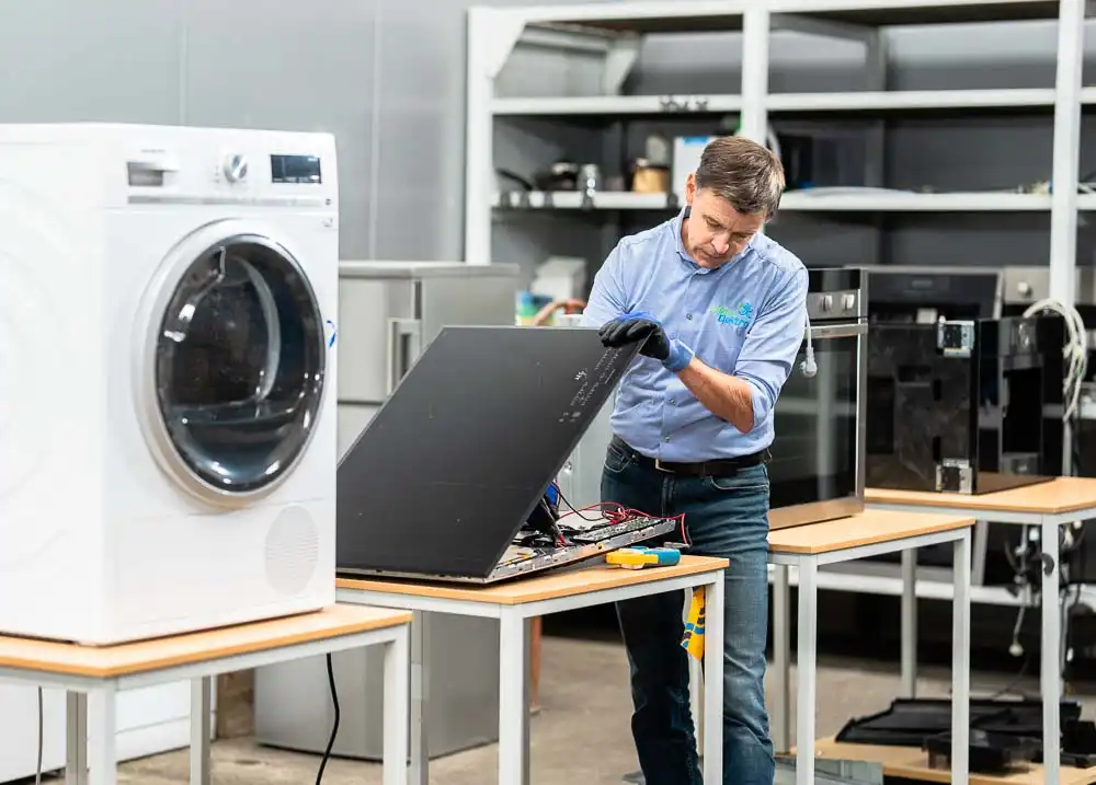 Marc Leyre - elektrohersteller - repareert een inductie kookplaat in zijn herstelcentrum in Gent.