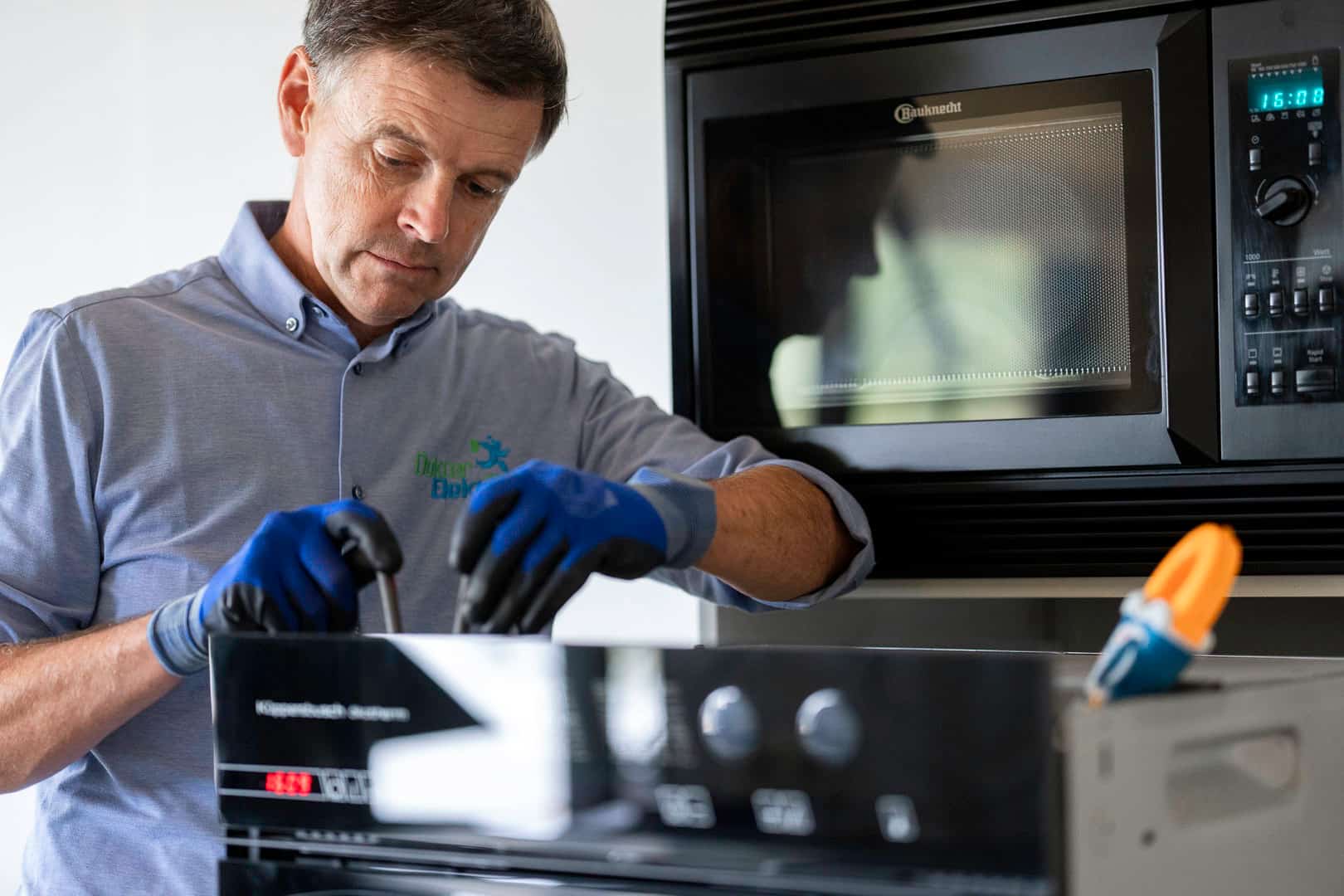 Dokter Elektro Marc Leyre herstelt een inbouwoven bij een klant aan huis. Hij herstelt huishoudapparaten in Gent en omtreken, Oost- en West-Vlaanderen