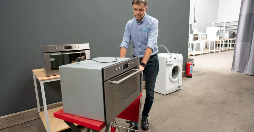 Marc Leyre vervoert een huishoudtoestel in zijn repaircentrum.